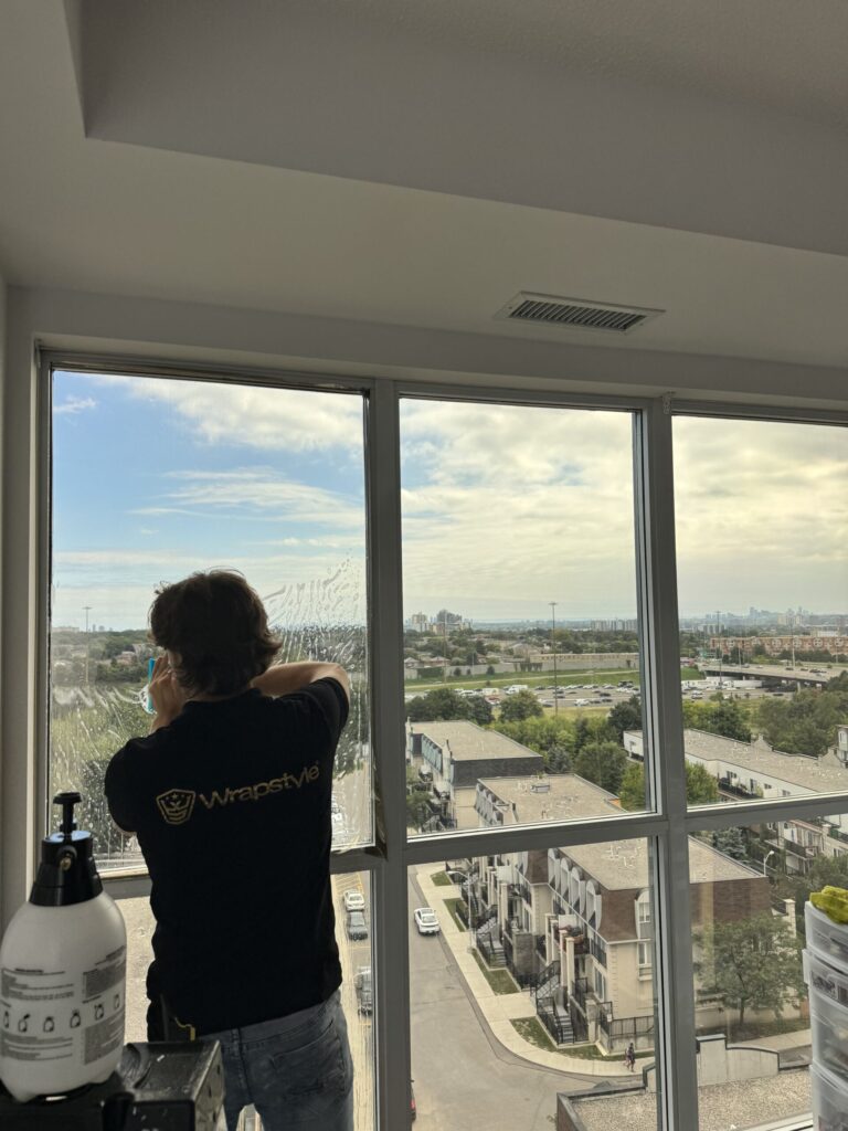 Professional technician applying window film inside a high-rise condo by WrapStyle Home.